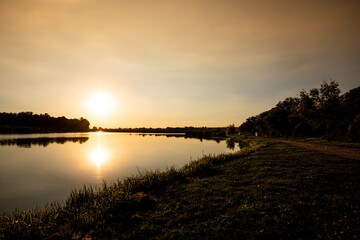 Scenic view of Sunset above the lake. Sun reflecting out of water surface. Landscape photo