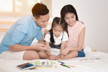 Happy family in the bedroom,Asian father and mother teaching her daughter child to studying at home.Photo series of family, kids and happy people concept.