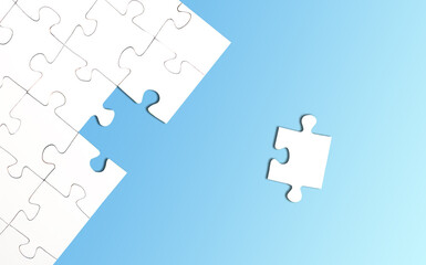 top view of incomplete jigsaw puzzle with one piece left on bright blue background, completing a...
