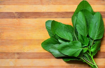 Fresh harvested tender green spinach placed on a wooden board. top view.