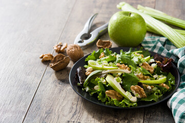 Fresh Waldorf salad with lettuce, green apples, walnuts and celery on wooden table