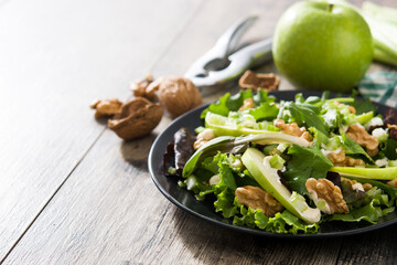 Fresh Waldorf salad with lettuce, green apples, walnuts and celery on wooden table