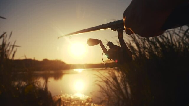 fisherman fishing fish silhouette on sunset. man recreation with fishing rod lifestyle outdoor catching fish at sunrise. hobbies fishing sport concept sunset. man relaxes with fishing rod