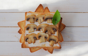 Mushroom toasts with creamy chees spread and  basil on the white wooden surface. Horizontal top view
