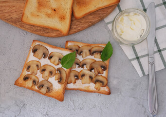 Mushroom toasts with creamy chees spread and  basil on the table. Horizontal top view
