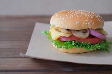 Burger with mushrooms, tomatos, lettuce, onion and cheese on dark wooden background. Horizontal view.