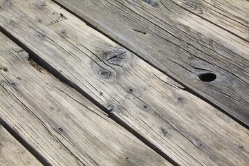 Wooden flooring made of old boards with knots and cracks, weathered by sand