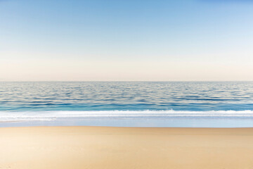 Fototapeta na wymiar Soft wave of blue ocean on the sandy beach and soft blue sky with copy space for text