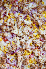Very tasty and appetizing pizza with ham, red onion, corn, cheese. Thin Italian pastry. Close-up, top view.