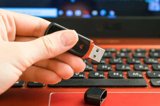 Usb flash drive in hand on background notebook