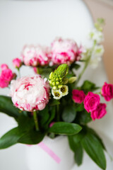 A beautiful bouquet of tender pink peonies and small roses stands on a white chair. Wedding bouquet, birthday. Close-up.