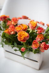 Bright red-orange rose, delicate bouquet in a wooden basket