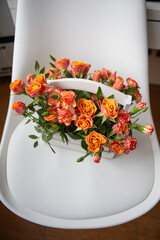 Bright red-orange rose, delicate bouquet in a white wooden basket