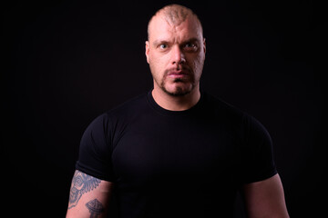 Obraz premium Portrait of muscular bald man against black background