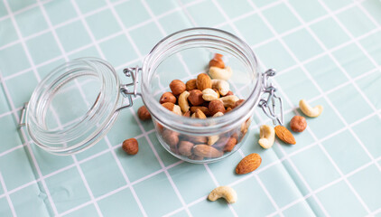 Mix of nuts in a glass jar. Cashews, hazelnuts and almonds. Selective focus, copy space. The concept of vegetarian and organic food.