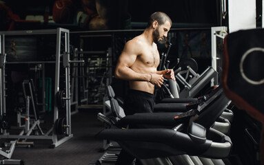 Fototapeta na wymiar Man running in a gym on a treadmill concept for exercising, fitness and healthy lifestyle