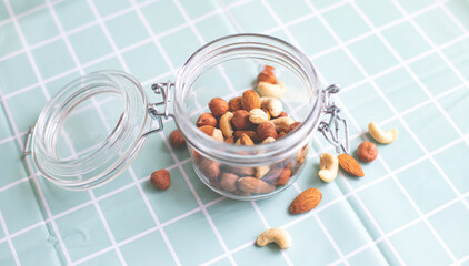 Mix of nuts in a glass jar. Cashews, hazelnuts and almonds. Selective focus, copy space. The concept of vegetarian and organic food.