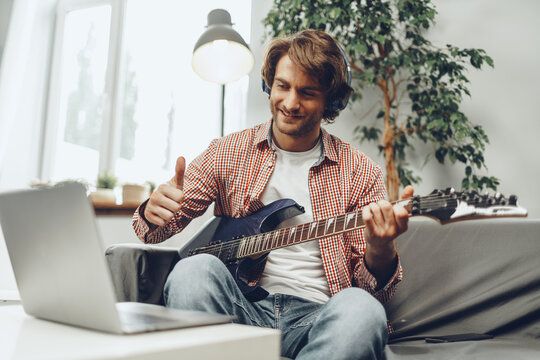 Man playing electric guitar and recording music into laptop