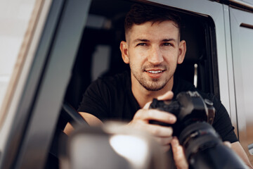 Attractive man photographer taking a photo while sitting in his car