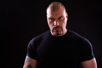 Obraz premium Face of muscular bald bearded man against black background