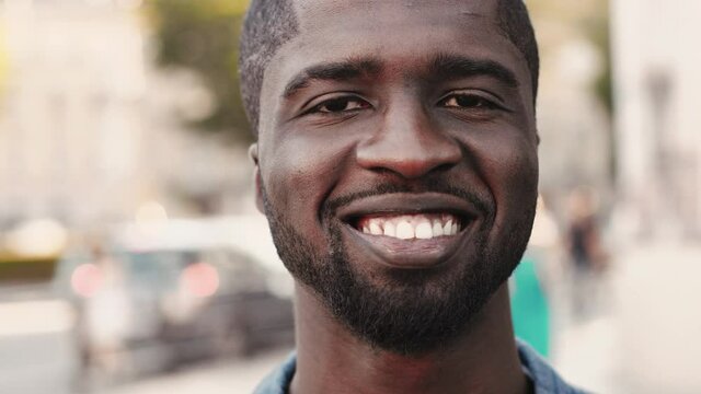 Close up portrait of young cheerful handsome African American man. Confident attractive guy smiling with white teeth.