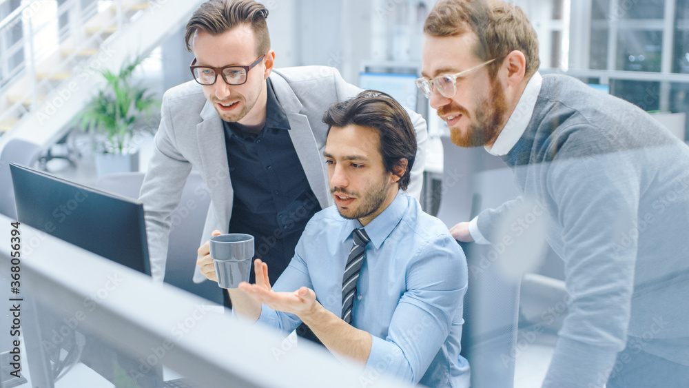 Poster In Bright Modern Office: Office Worker Sitting and Working at His Desktop Computer, Discusses Problem Solution with His Project Manager and Team Leader. Young Businessmen Planning and Problem Solving