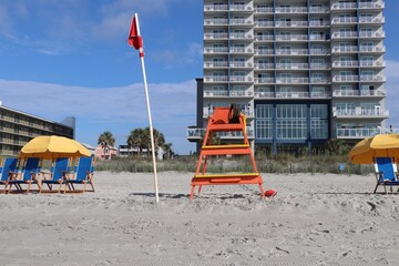 Lifeguard station with umbrellas and lounging chairs on the beach with hotels in the background 