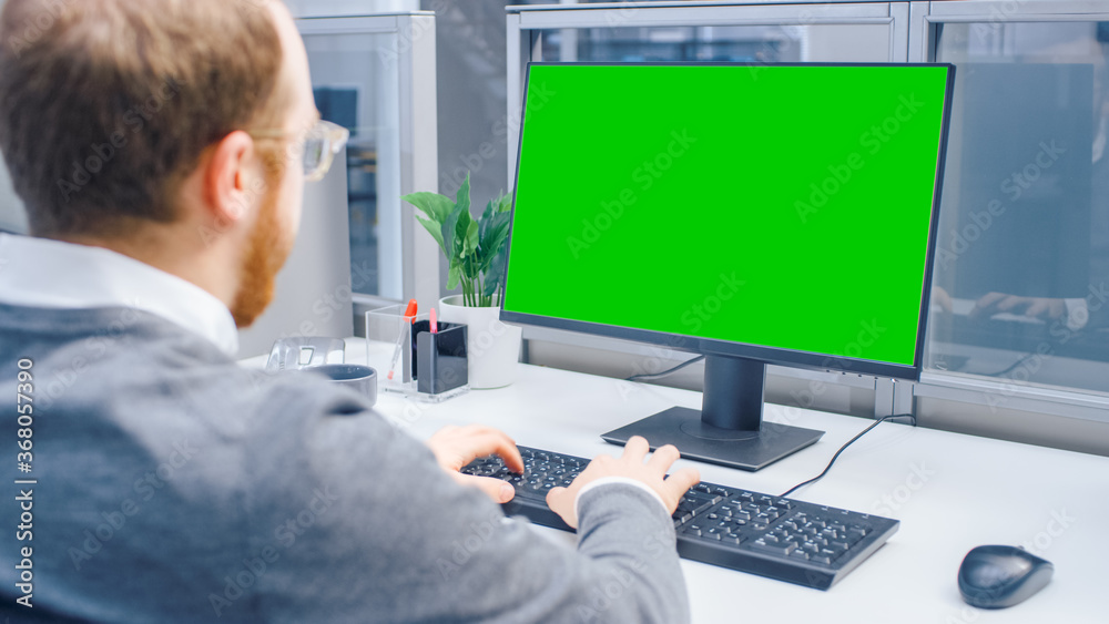 Poster Over the Shoulder Shot of Motivated Office Worker Using Green Mock-up Screen Desktop Computer in the Big Bright Open Space Office