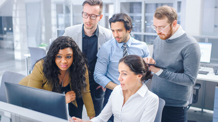 In Modern Office: Diverse Team of Young Motivated Businessmen and Businesswoman Work on Computer, Having Discussion, Finding Problem Solution Collectively. Ambitious Businesspeople Successful Teamwork