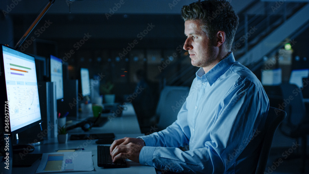 Poster portrait of ambitious and confident businessman uses desktop computer, typing on a keyboard, monitor
