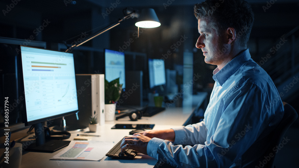 Poster portrait of ambitious and confident businessman uses desktop computer, typing on a keyboard, monitor