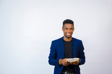 a young handsome african businessman isolated over white background smiles as he holds his tablet