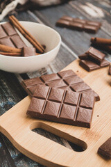 milk dark chocolate tiles on wood cutting board, wooden background