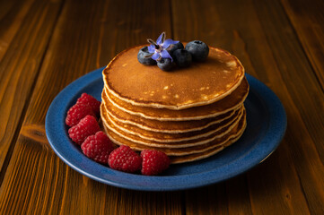 Fresh pancakes with berries on the wooden table. Closeup view. Low Key Food Photography