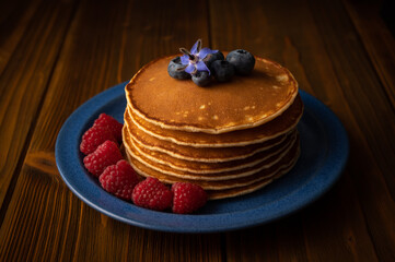Fresh pancakes with berries on the wooden table. Closeup view. Low Key Food Photography