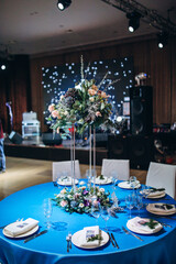 Flower decoration of wedding tables.
Banquet table setting and decoration. Cutlery on the table. Blue interior decoration. New Year's decoration.