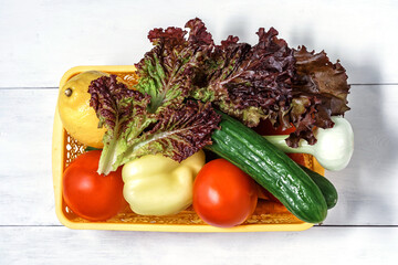 vegetables for salad in a basket on a wooden background