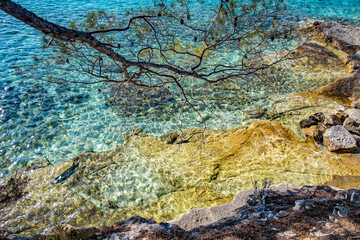 Aerial view of a slide turn from a drone on the view of calm turquoise sea water and rocks from molten lava. Pattern of sea surface and rocky shore.