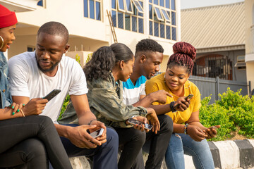 group of young african friends talking and using their mobile phones