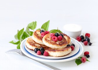 Cottage cheese pancakes with fresh berries, raspberries and black currants on a white background 