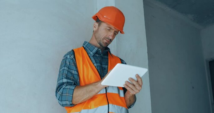 Handsome builder using digital tablet on construction site
