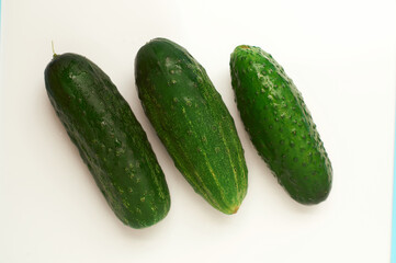 Three green cucumbers of different shapes on a white background.