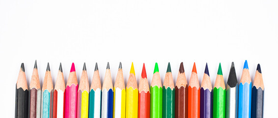 A line of different colored wood pencil crayons placed on a white background