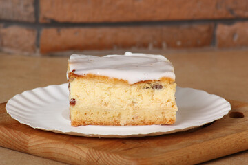 Cheesecake on disposable paper plate. Cheesecake with raisins topped with sugar icing.