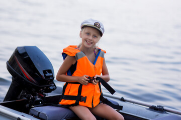 Happy little girl with life vests, having fun on a boat trip while on holiday in lake