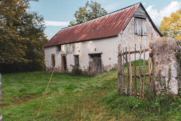 Abandoned old barn with wooden fence and grass on backyard. Weathered exterior of ancient building in village. Rural landmark. Rustic architecture in France. Travel in provence, France. Countryside.