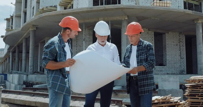 Engineer and builders discussing blueprint on construction site