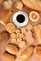 Assorted bread rolls, cookies and coffee cup at wooden plank background. Directly Above.