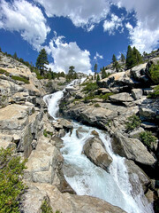 waterfall in the mountains with blue sky and white clouds