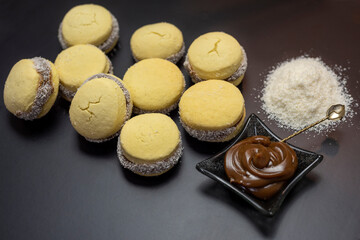 cornstarch alfajores with dulce de leche and grated coconut caramel on black background